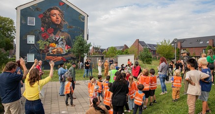 Museum Murals: Kunst aan de Marconistraat Een groep mensen in oranje vesten die zich voor een muurschildering bevinden